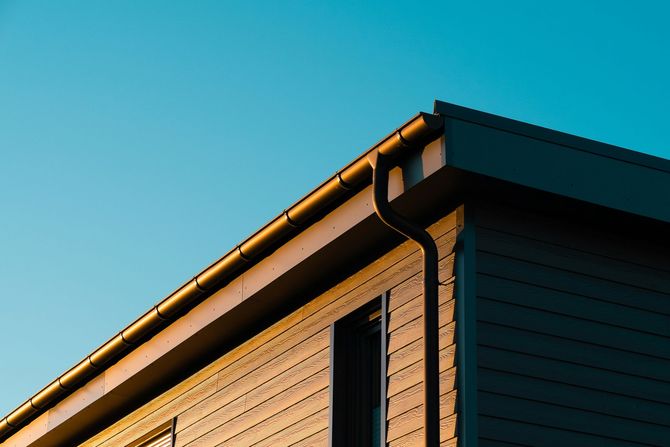 A traditional Asian-style tiled roof under a bright blue sky, topped with a decorative golden finial.