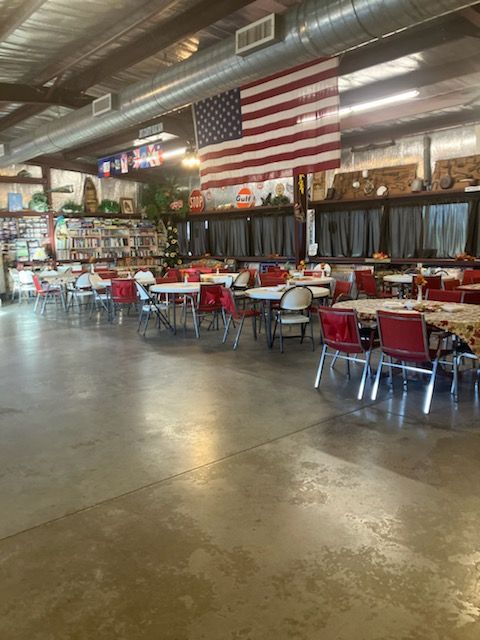 A large room with tables and chairs and an american flag hanging from the ceiling.