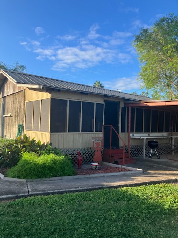 A mobile home with a screened in porch and a grill.