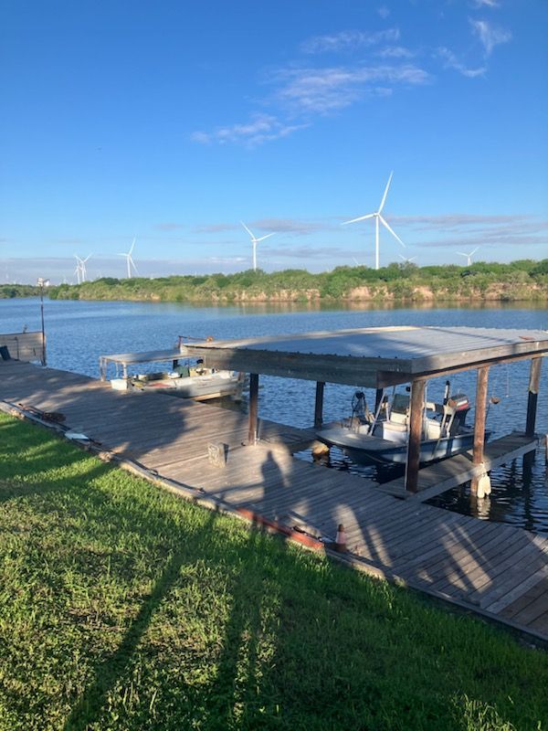 A boat is docked at a dock next to a lake with windmills in the background.