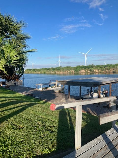 A wooden deck overlooking a body of water with windmills in the background.