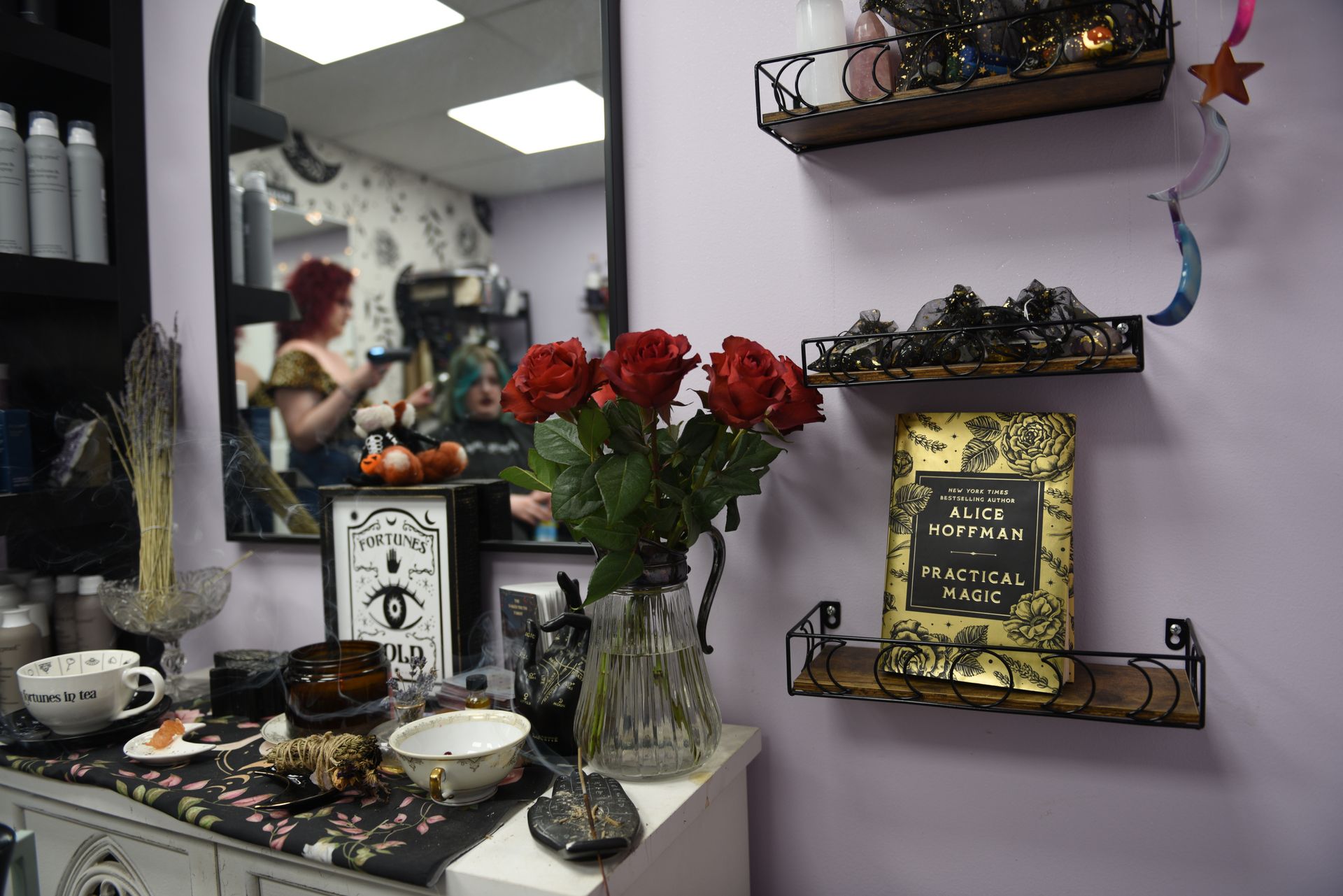 Hair salon interior with roses, a mirror reflecting a person, and decorative shelves.