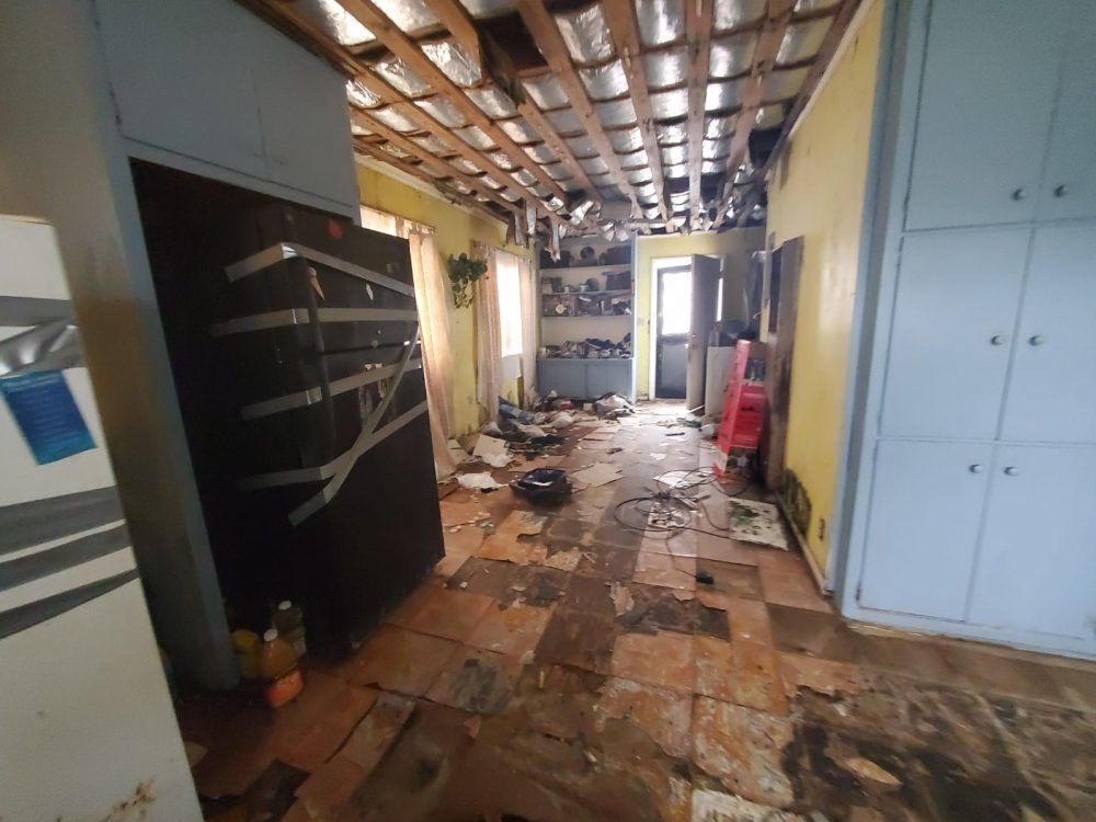 A kitchen with a refrigerator and a broken ceiling