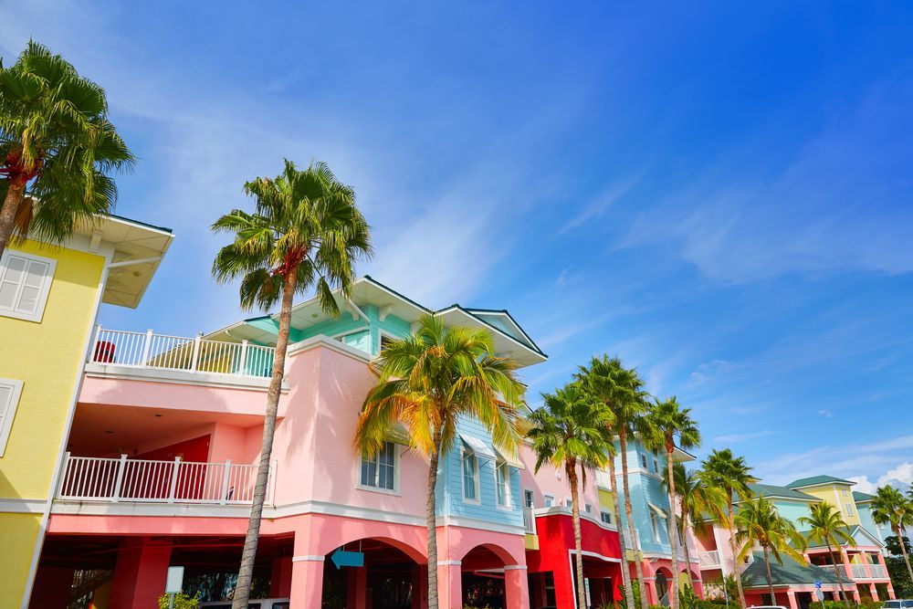 A row of colorful houses with palm trees in front of them on a sunny day.