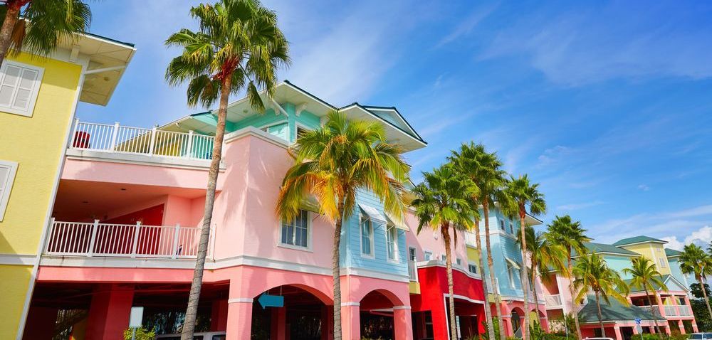 A row of colorful houses with palm trees in front of them on a sunny day.