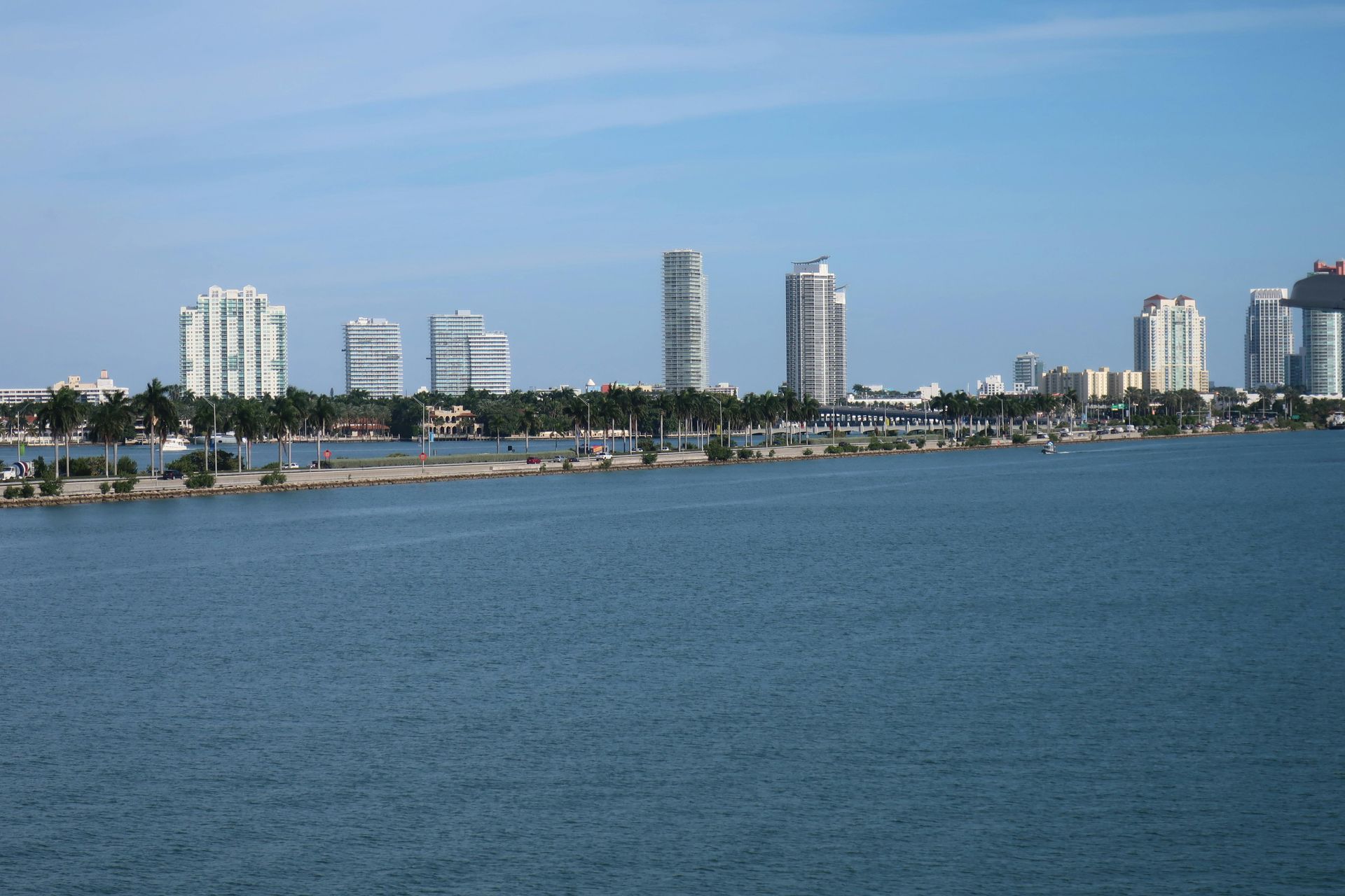 Skyline of a coastal city with tall buildings, a marina, and blue water under a clear sky.