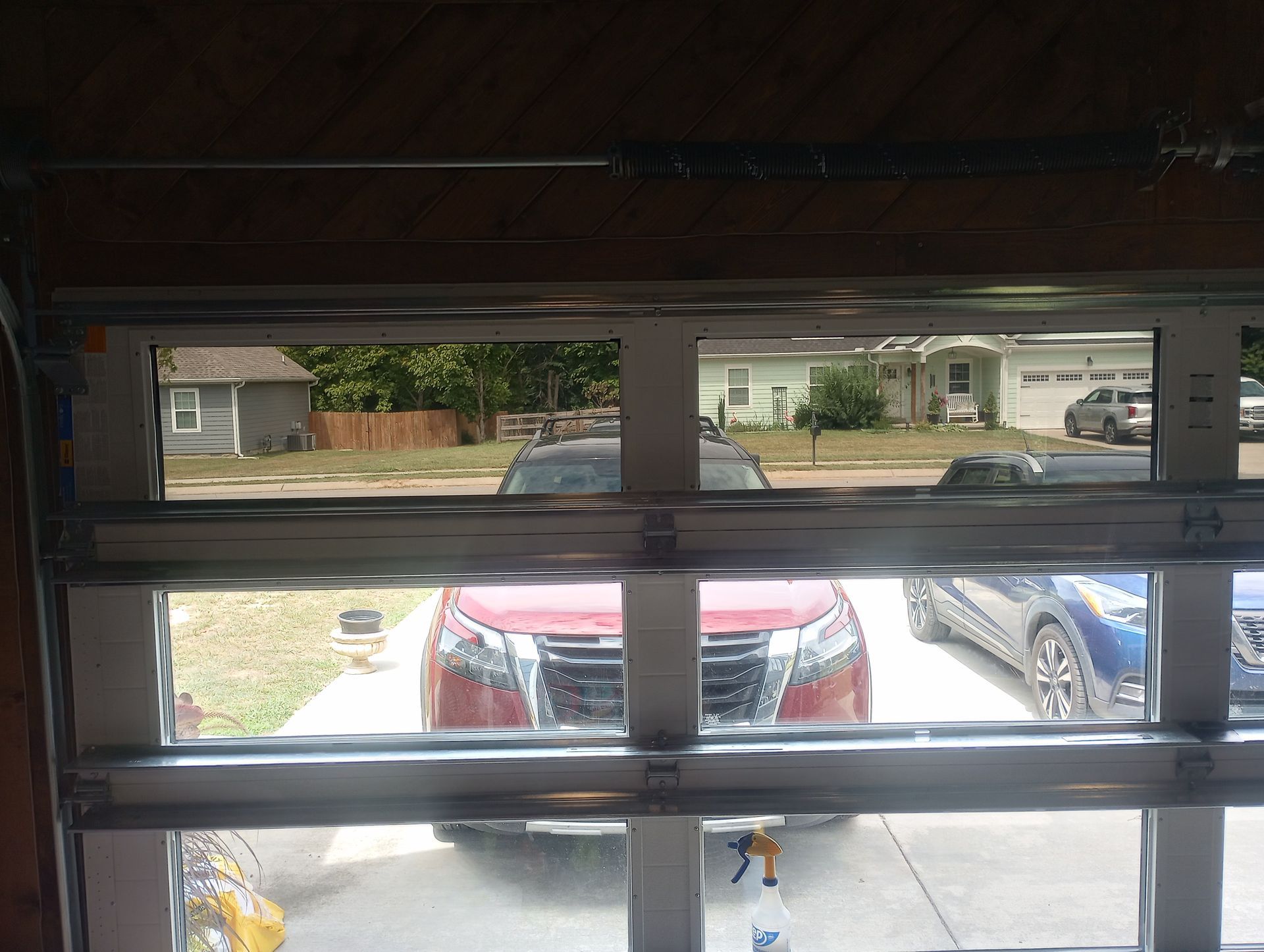 A red car is parked in front of a garage door.