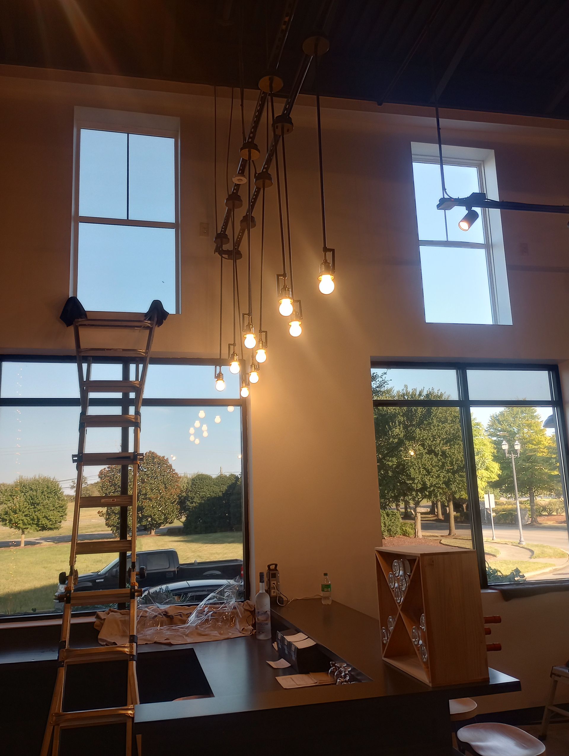 A kitchen with a ladder and lots of lights hanging from the ceiling