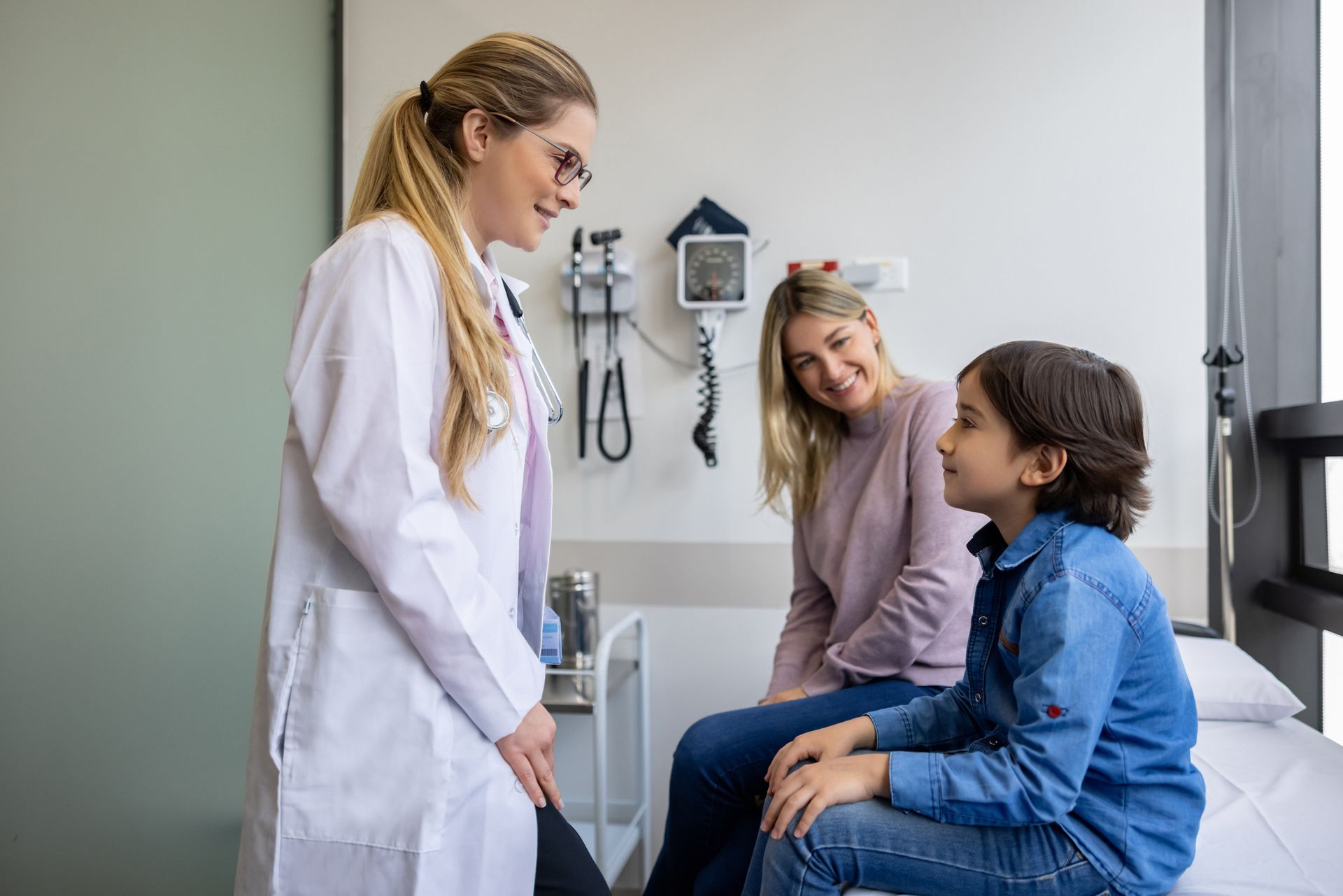 A doctor is talking to a woman and a boy in a hospital room.