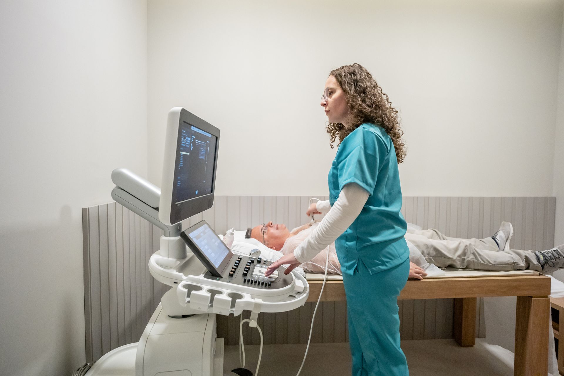 A nurse is using an ultrasound machine on a patient.