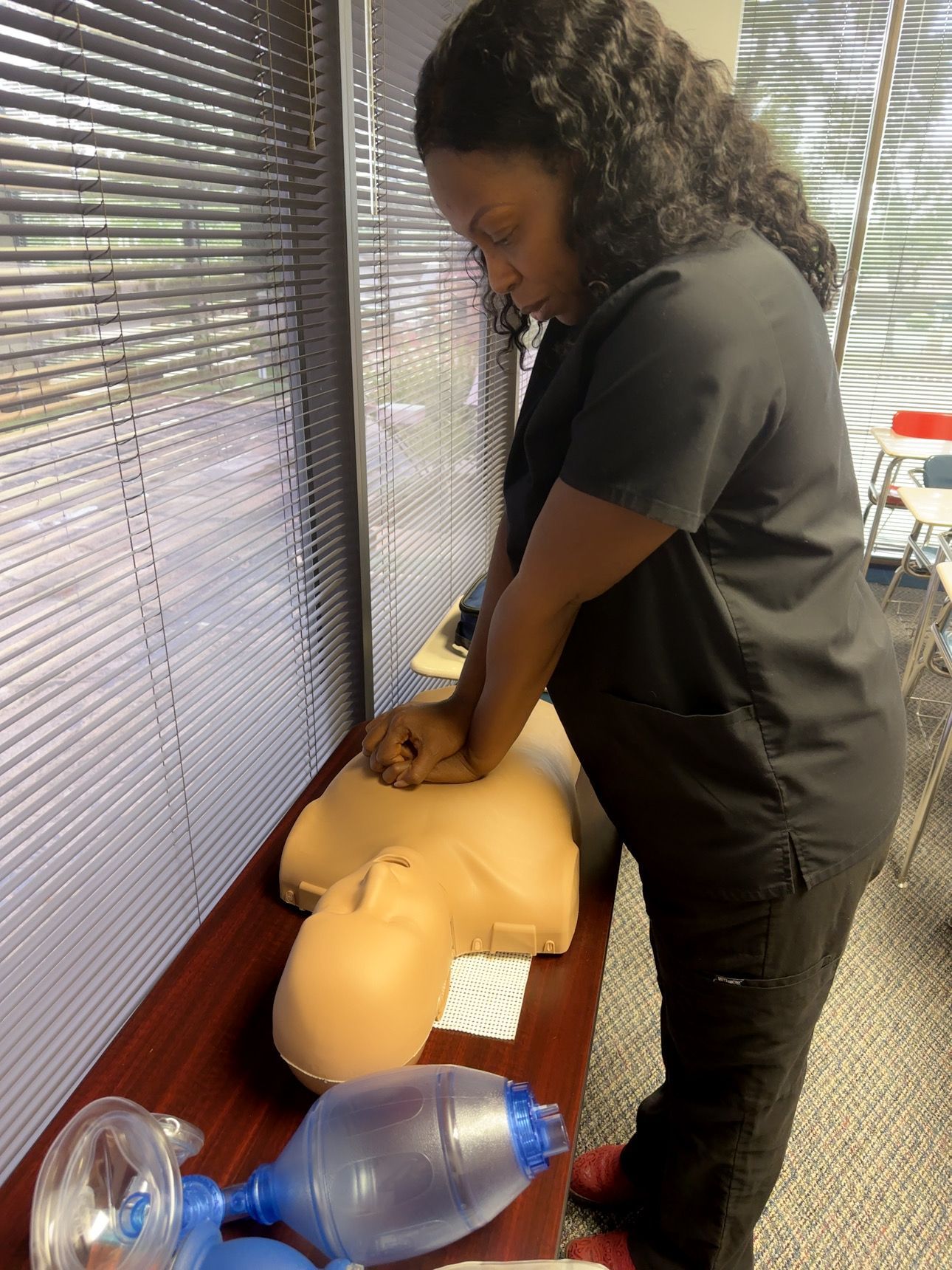 A woman is practicing a heart massage on a mannequin.