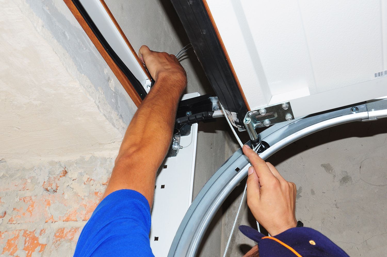 Technician adjusting hardware on a garage door track.