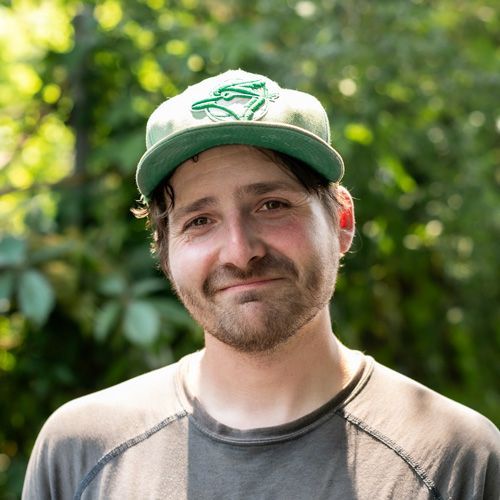 A man wearing a green hat and a gray shirt is smiling for the camera.