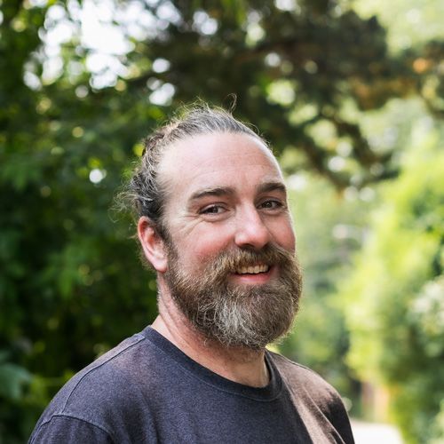 A man with a beard and ponytail is smiling for the camera.