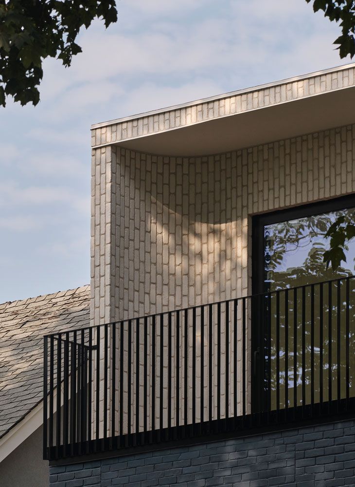 Modern building exterior with a brick facade, balcony, and large window.