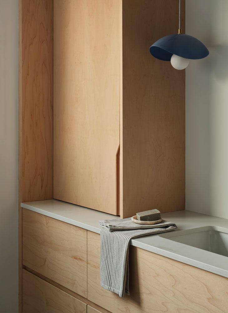 Wooden cabinetry in a bathroom with a sink and dark blue pendant light.