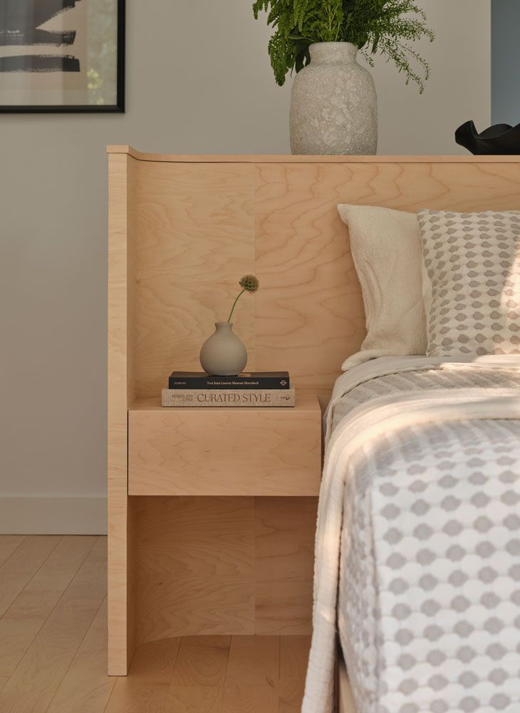 Wooden bed with attached nightstand, vase of flowers, and book.
