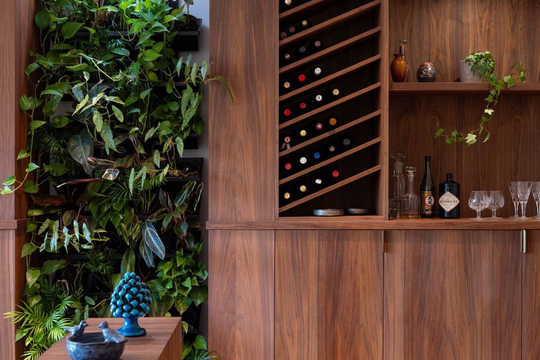A living room with a custom built-in wine rack and a wall of plants.