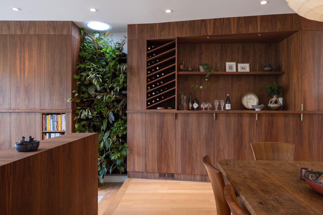 A dining room with a wooden table and chairs and a wine rack.