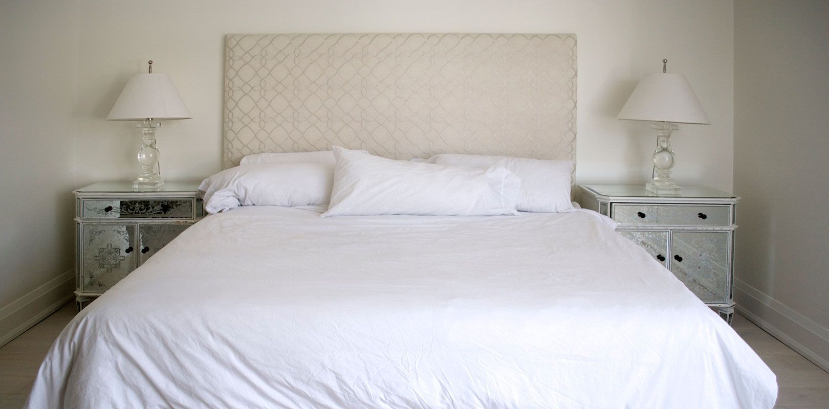 A bedroom with a bed , two nightstands and two lamps.