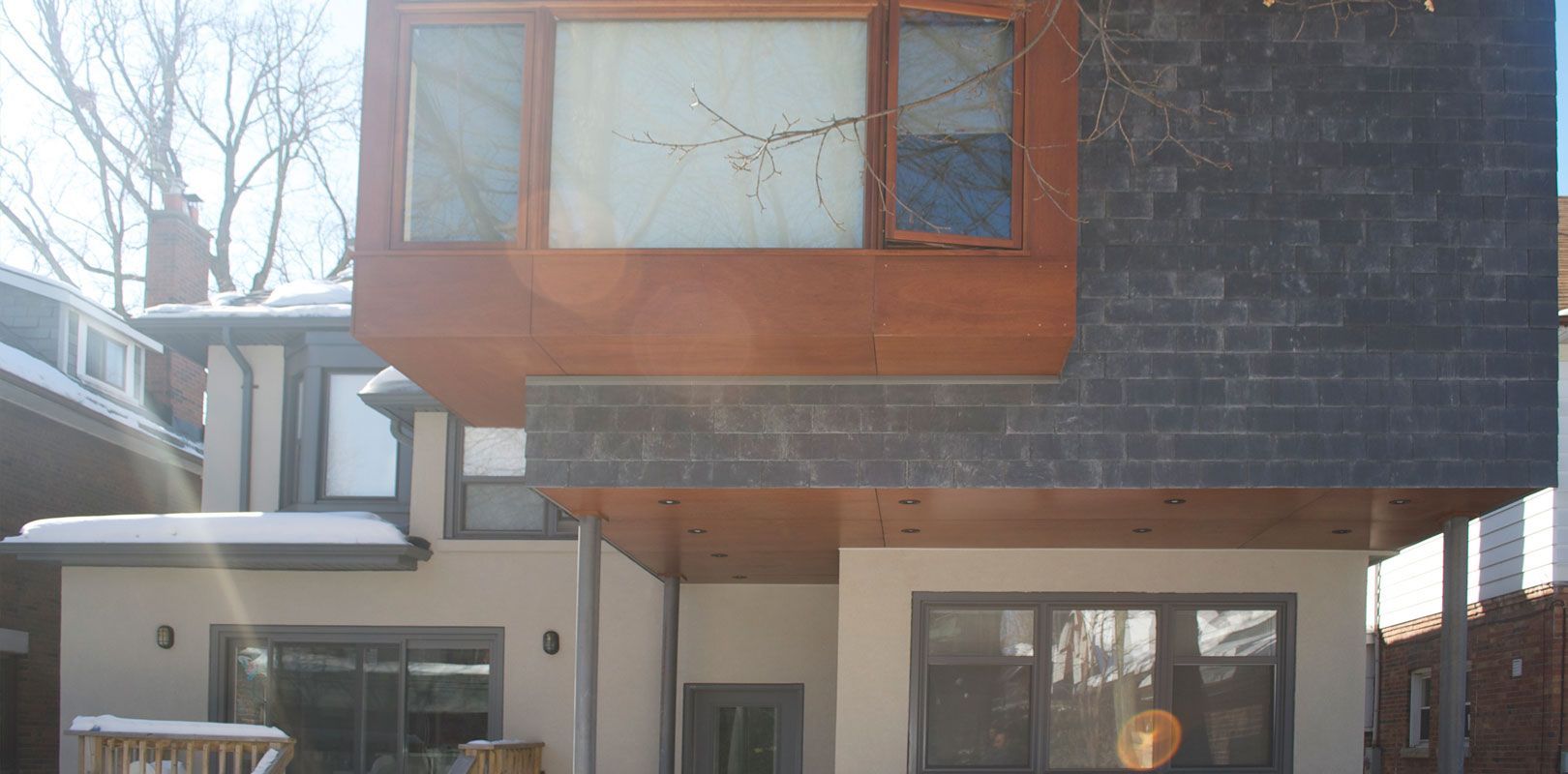A house with a lot of windows and a roof that is covered in snow.