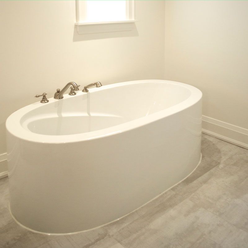 A white bathtub in a bathroom next to a window