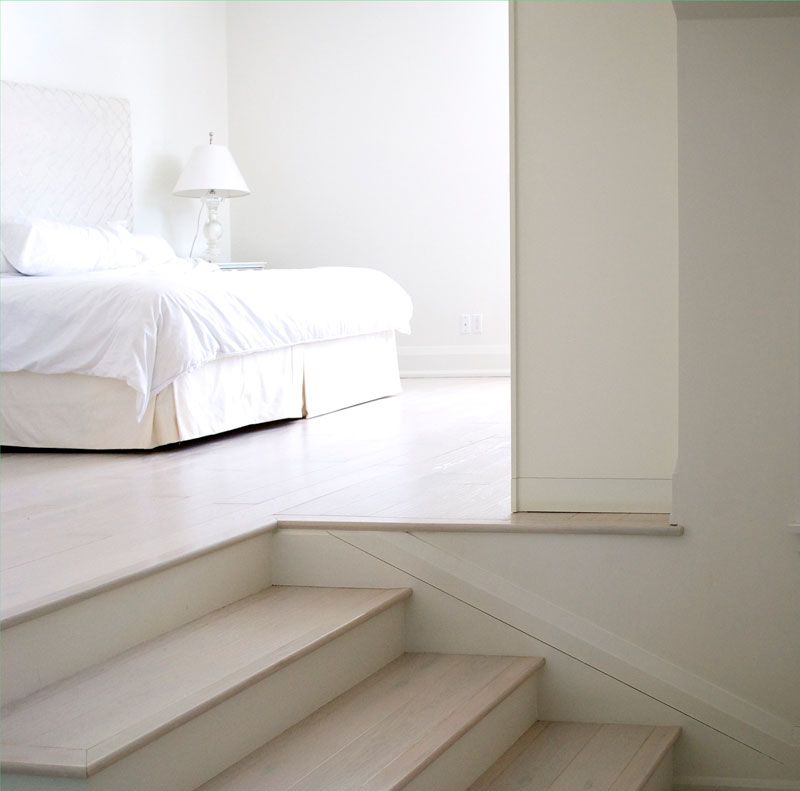 A bedroom with a bed and stairs leading up to it