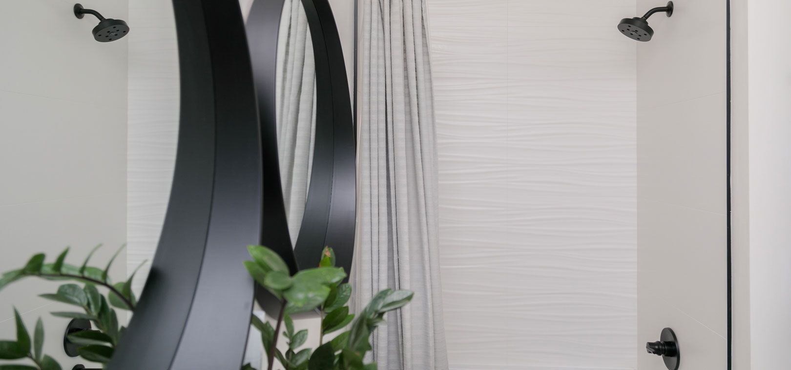 A bathroom with a shower , mirror , and plant.