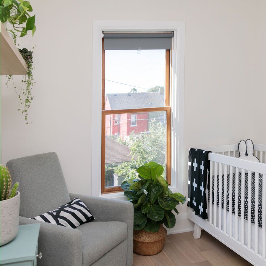 A room with a crib a chair and a window