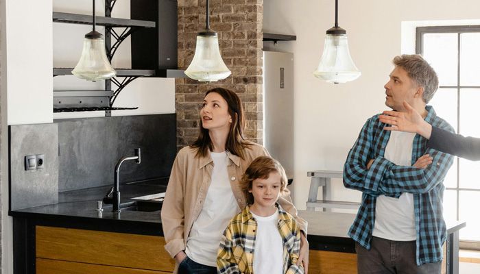 A family is standing in a kitchen looking up at the ceiling.