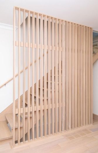 A wooden railing surrounds a staircase in a house.