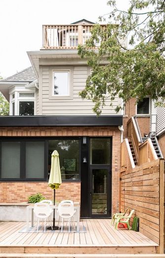 The back of a house with a wooden deck and chairs.