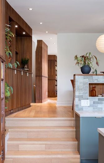 A kitchen with wooden cabinets and stairs leading up to it