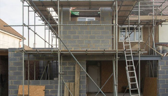 A house is being built with scaffolding and a ladder.