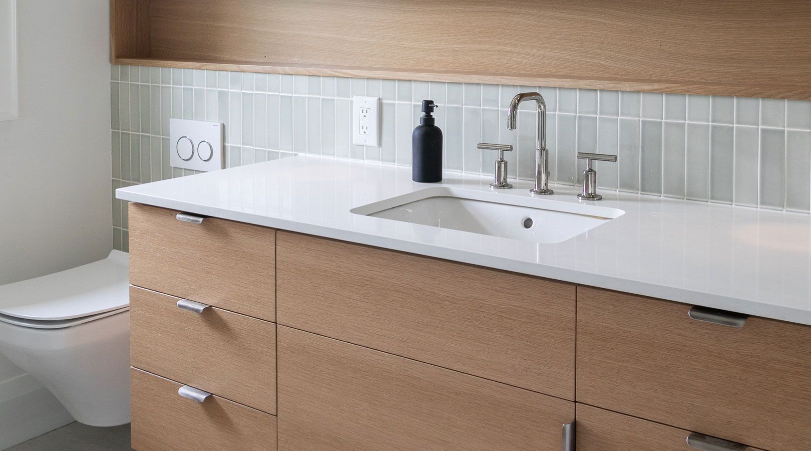 A bathroom with a sink , toilet , and cabinets.