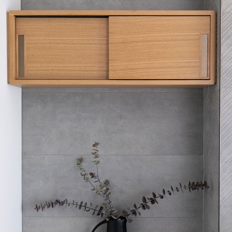 A vase of flowers sits under a wooden shelf