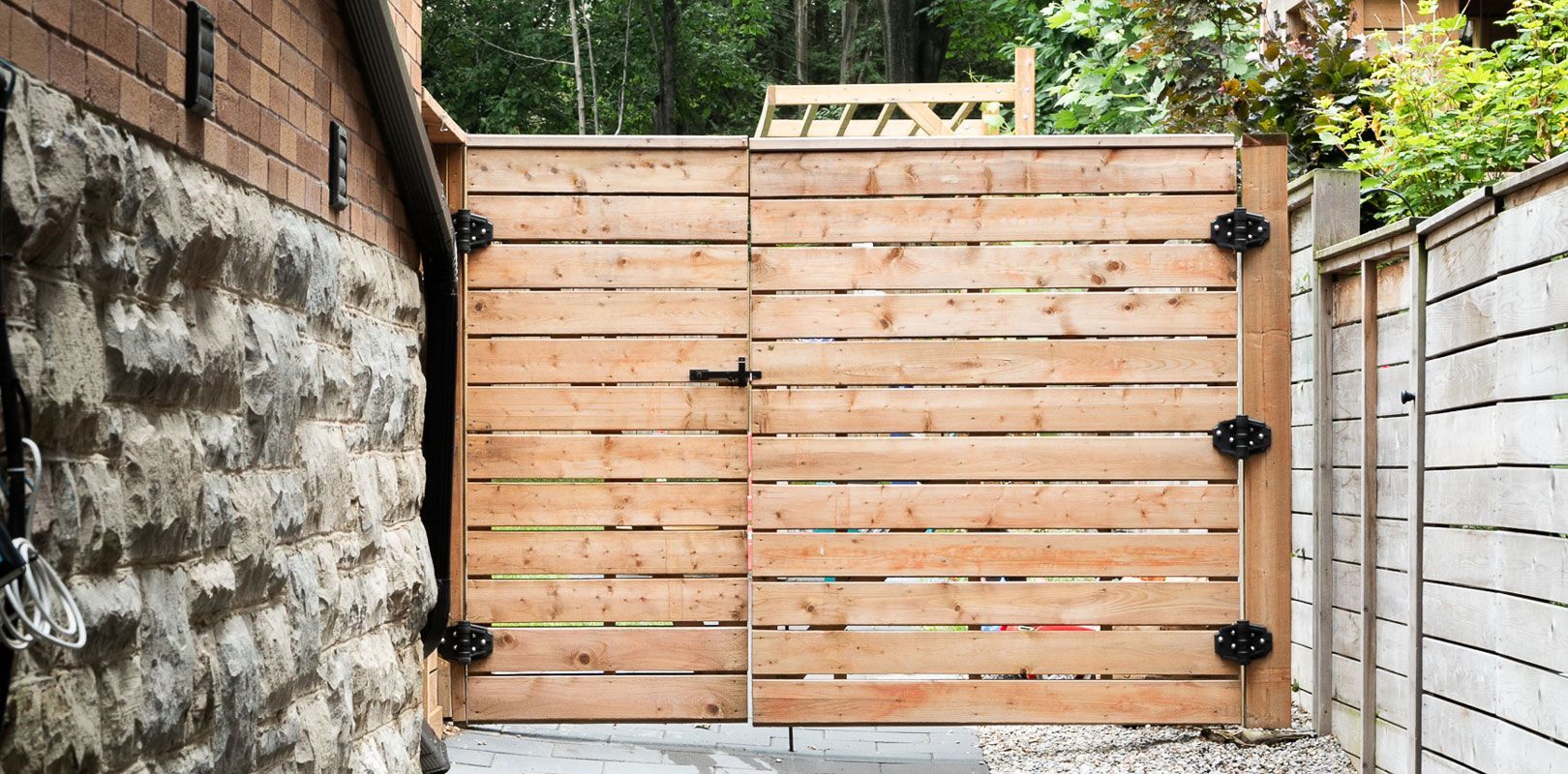 A wooden gate is sitting next to a stone wall.