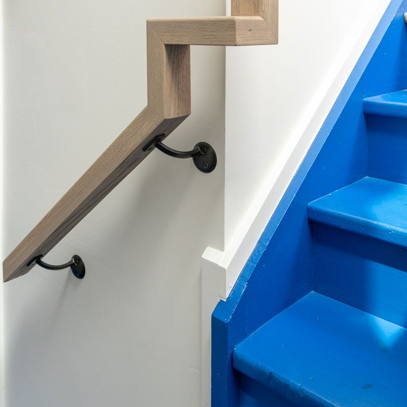 A blue staircase with a wooden railing and a white wall