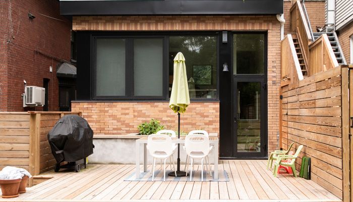 A patio with wicker chairs and a wooden table