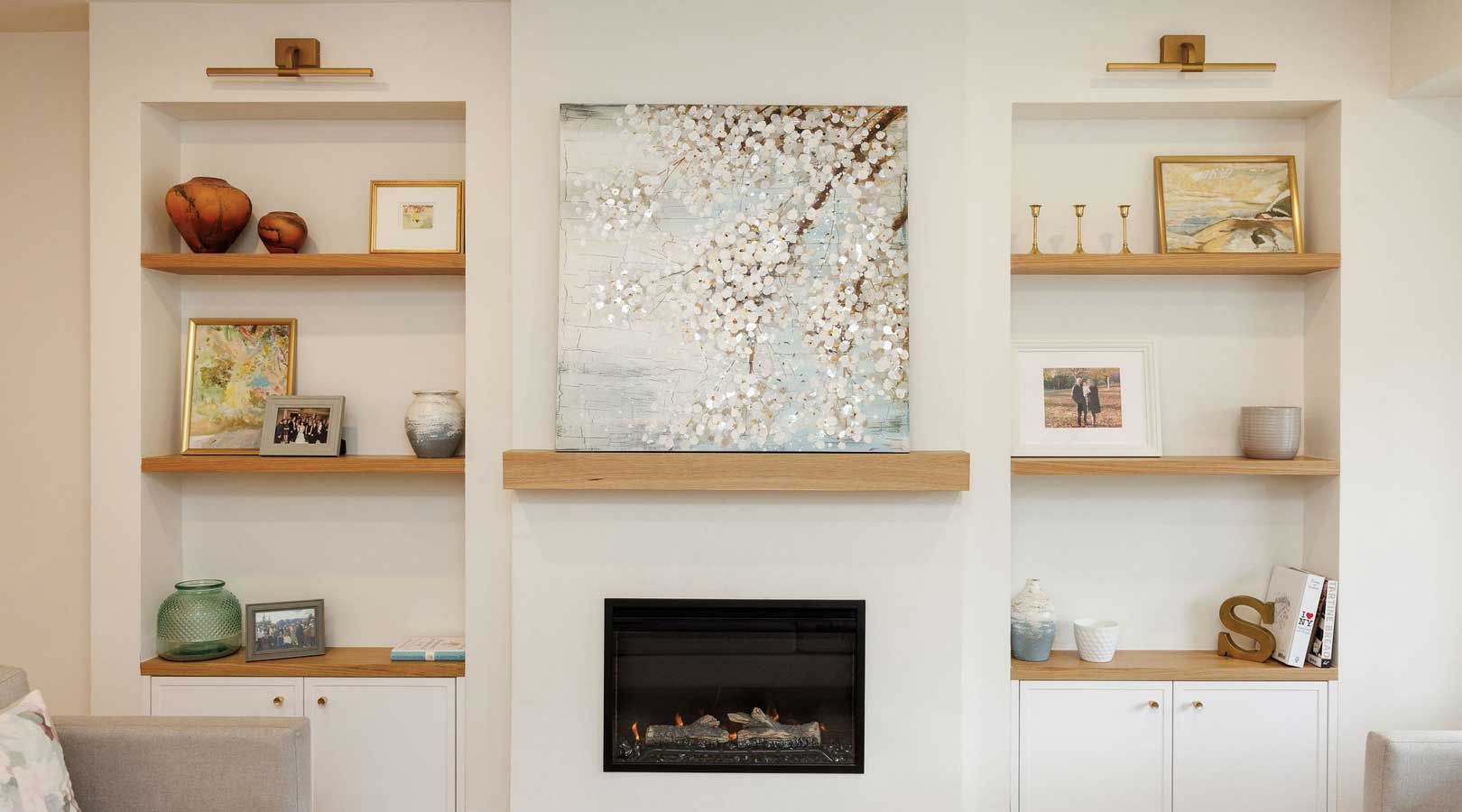 A living room with a fireplace , shelves , and a painting on the wall.