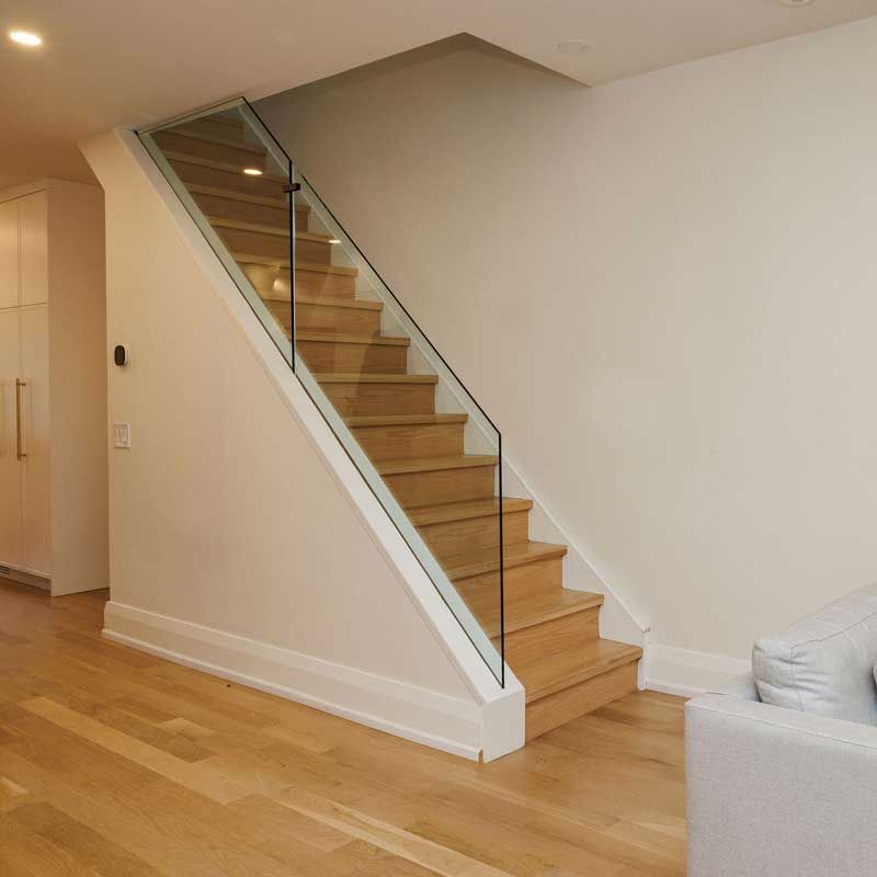 A wooden staircase with a glass railing in a living room.
