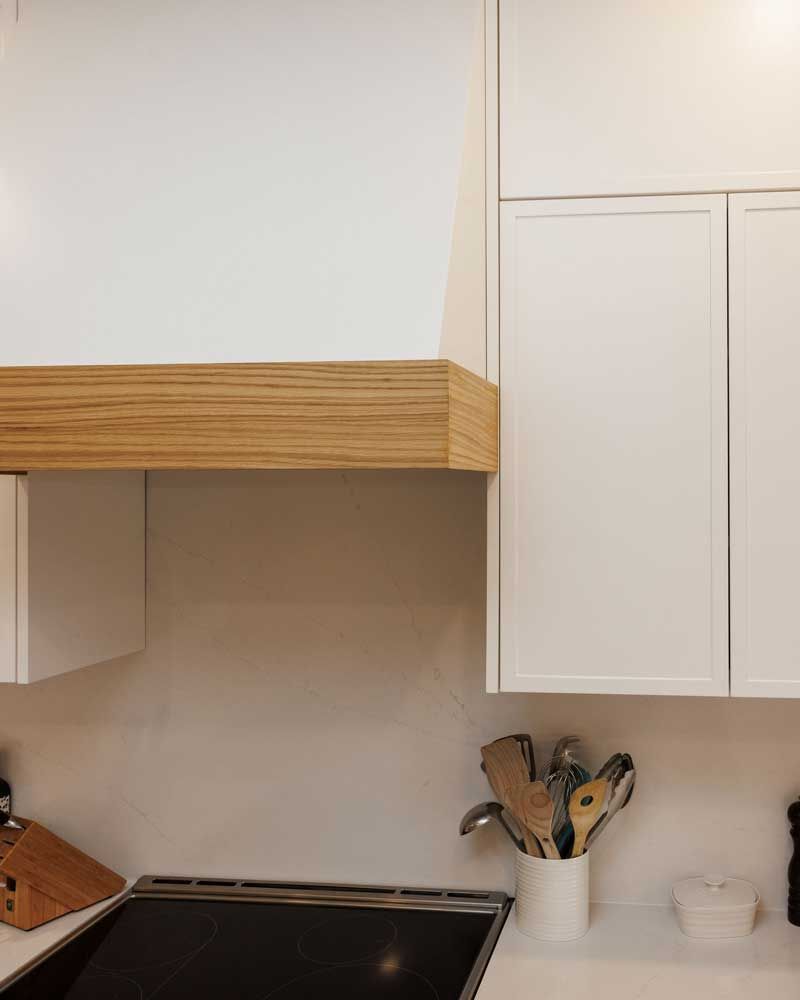 A kitchen with white cabinets and a stove top oven.