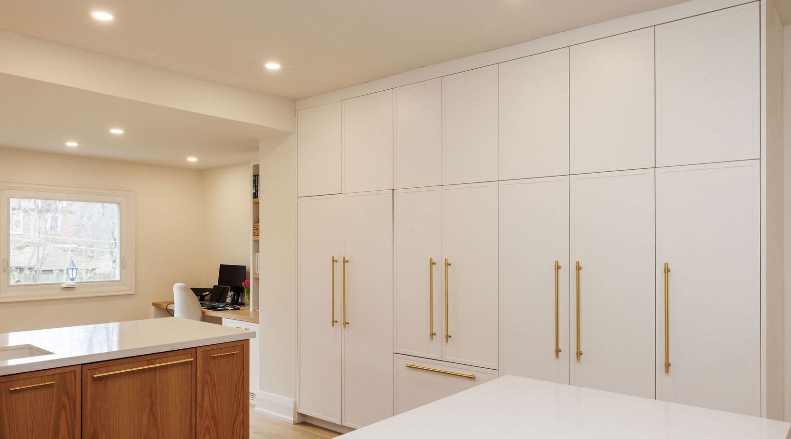 A kitchen with white cabinets and wooden cabinets and a large island.