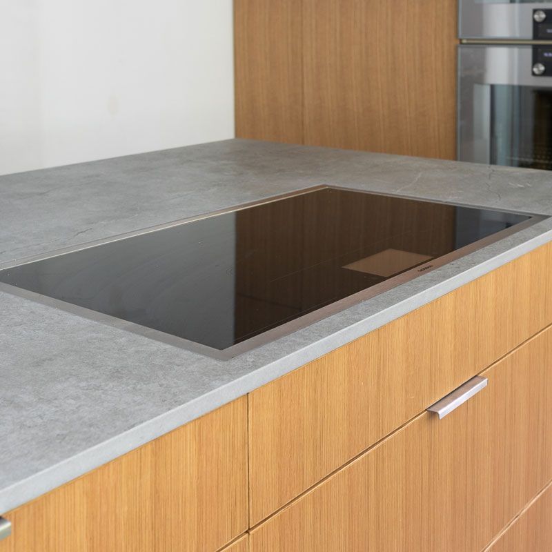 A kitchen counter with a stove top oven and wooden cabinets.