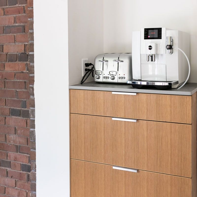 A toaster and a coffee maker sit on a wooden cabinet