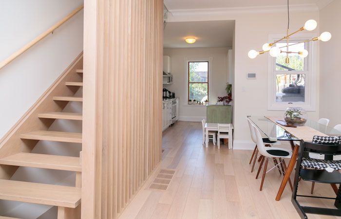 A wooden staircase leads to a dining room with a table and chairs.