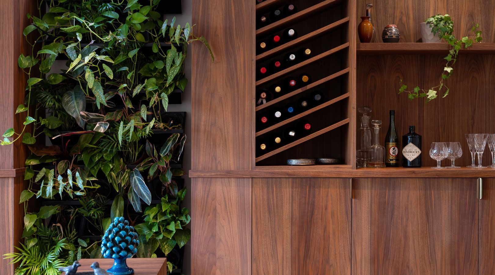 A living room with a wall of plants and a wine rack.