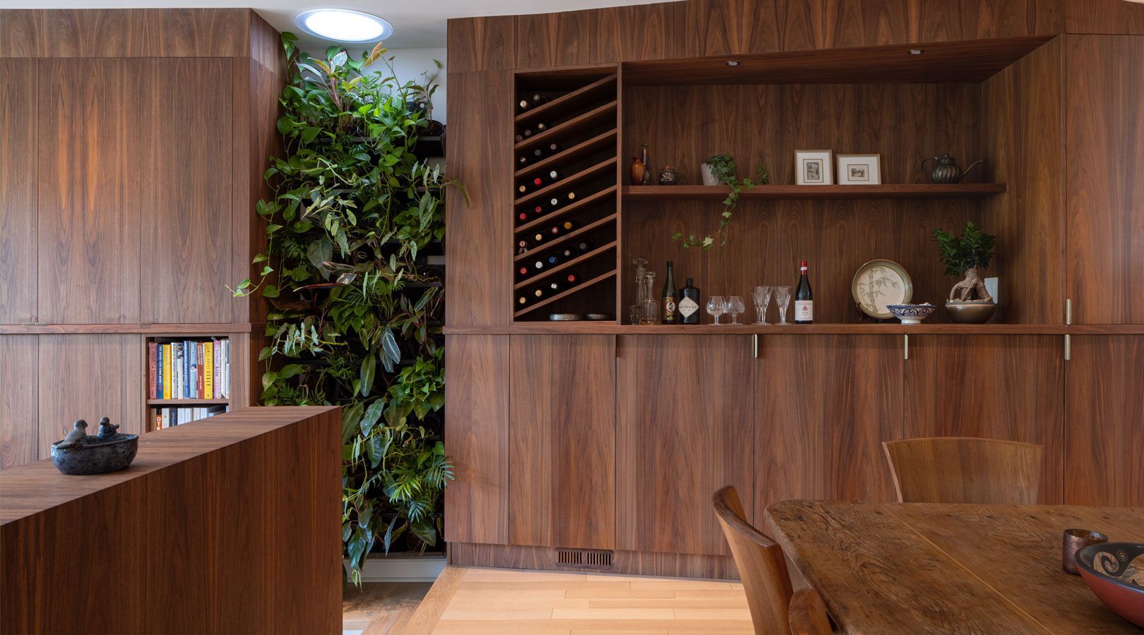 A dining room with a wooden table and chairs and a wine rack.