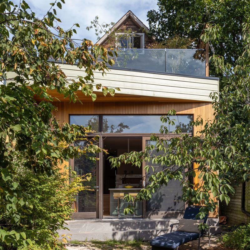 A house with a balcony is surrounded by trees