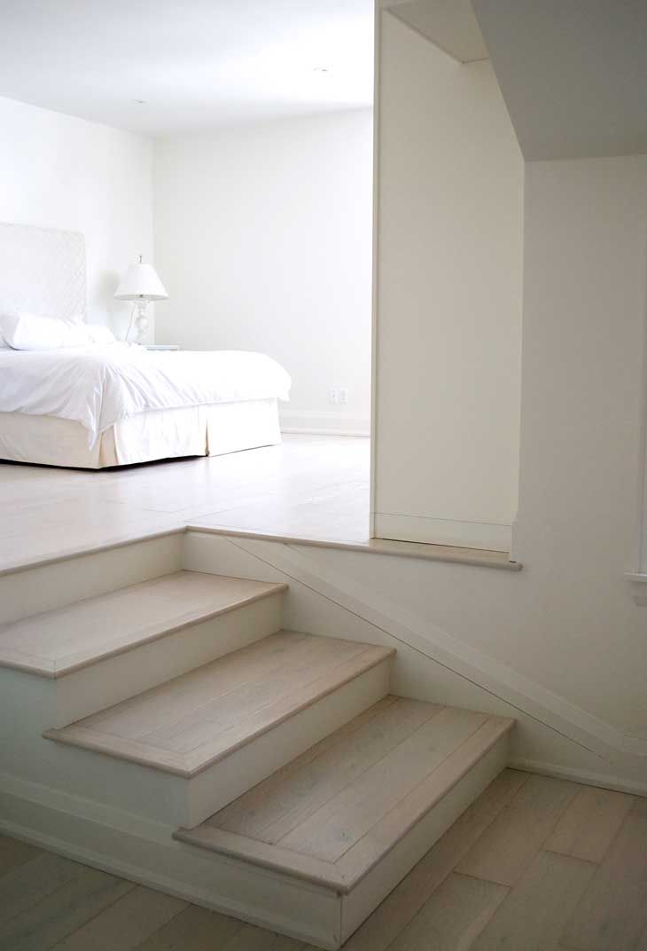 A bedroom with a bed and stairs leading up to it.